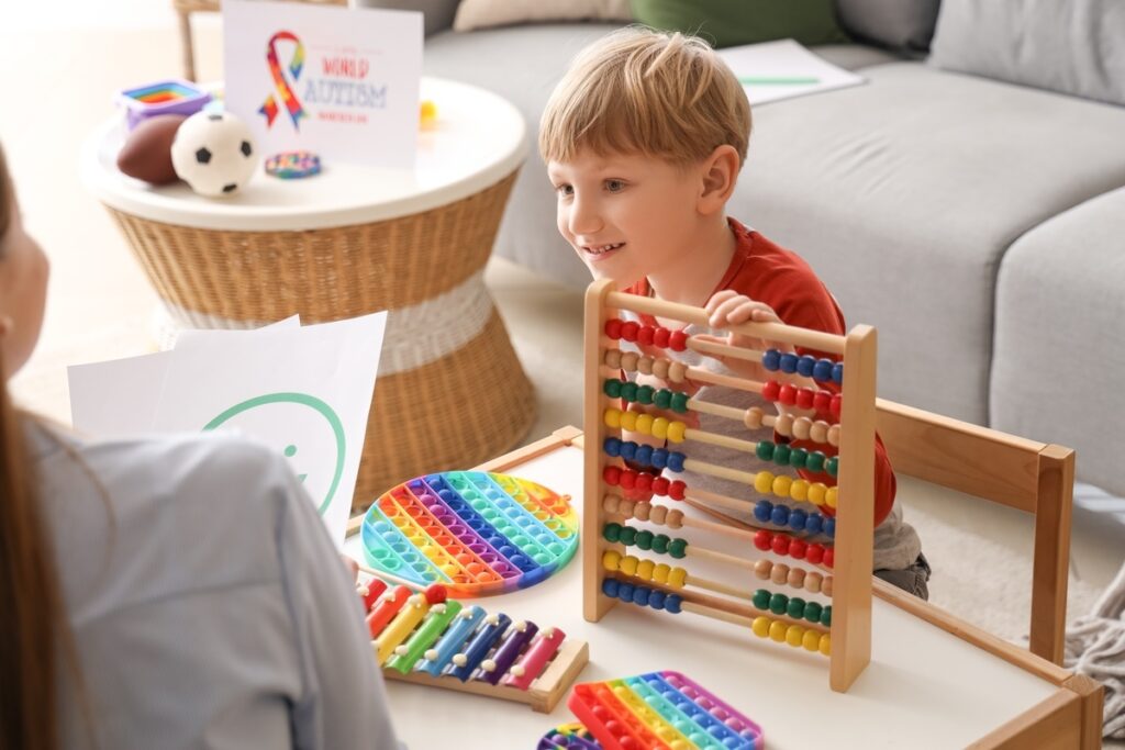 A young boy engaging with an abacus and colorful sensory toys during an autism screening and diagnostic tools evaluation session with a clinician