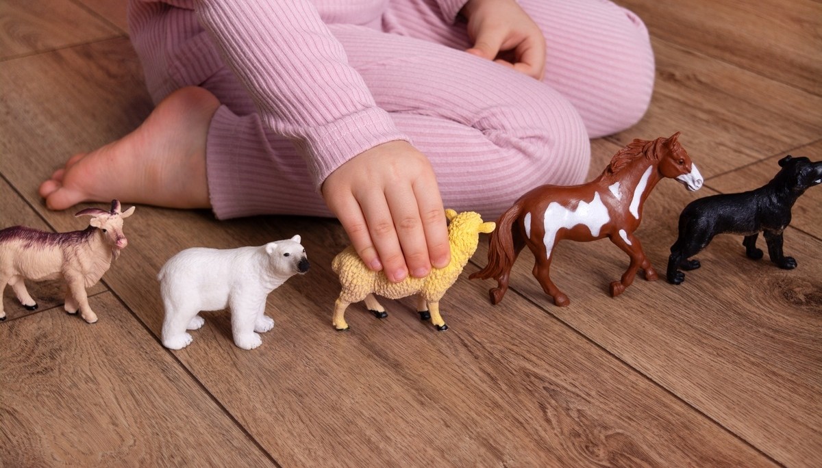 A young child sitting on the floor lining up animal figurines, a repetitive play behavior commonly associated with high functioning autism in children