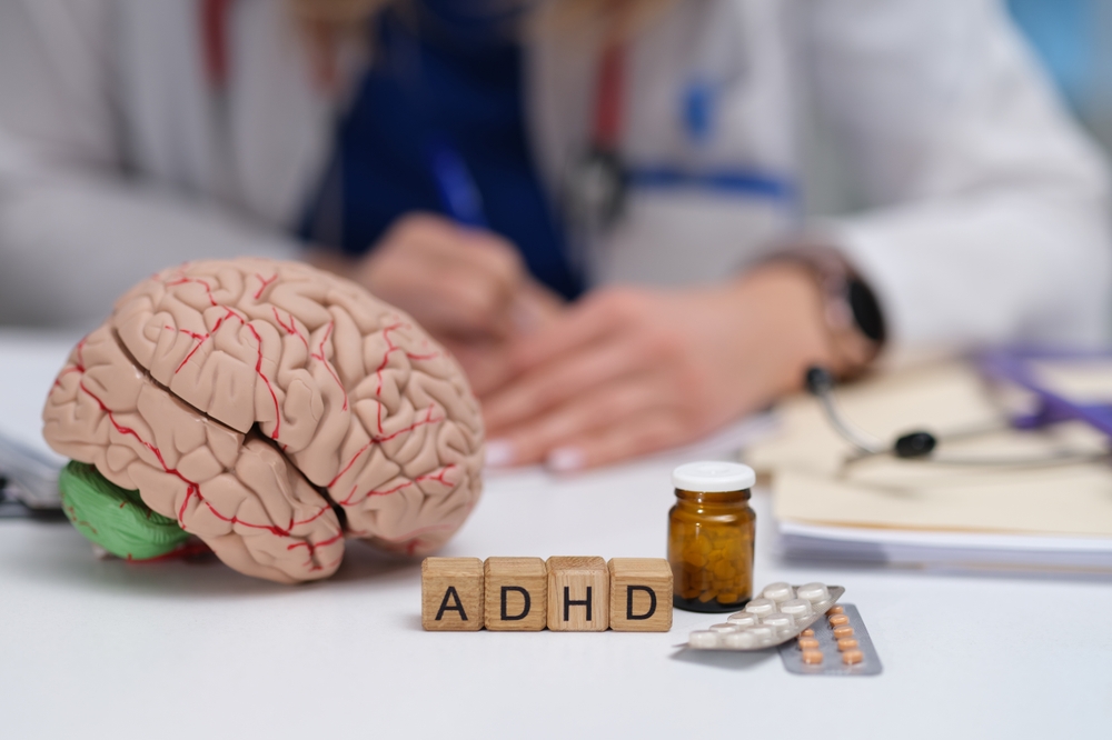 Brain model and ADHD letter blocks on a desk representing adult ADHD treatment with a psychiatrist