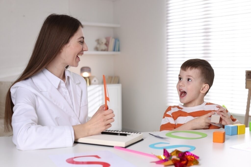 A therapist using visual cards and colorful learning materials during an ABA therapy for children session with a young boy
