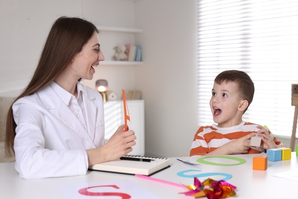 A therapist using visual cards and colorful learning materials during an ABA therapy for children session with a young boy